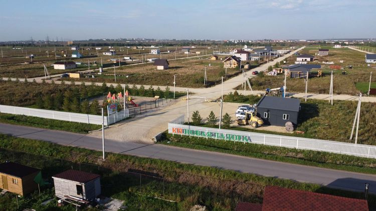 коттеджный посёлок Новая Ладога вид на главные ворота. Просторный въезд, широкая двуполосная дорога, территория посёлка обнесена забором